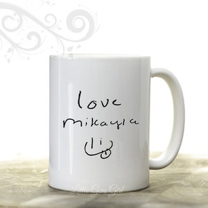 Może przedstawiać: Biały ceramiczny kubek z zakrzywionym uchwytem. Kubek ma odręczny tekst z napisem "love mikayla li" czarnym tuszem. Kubek ma błyszczące wykończenie i jest umieszczony na białym tle.