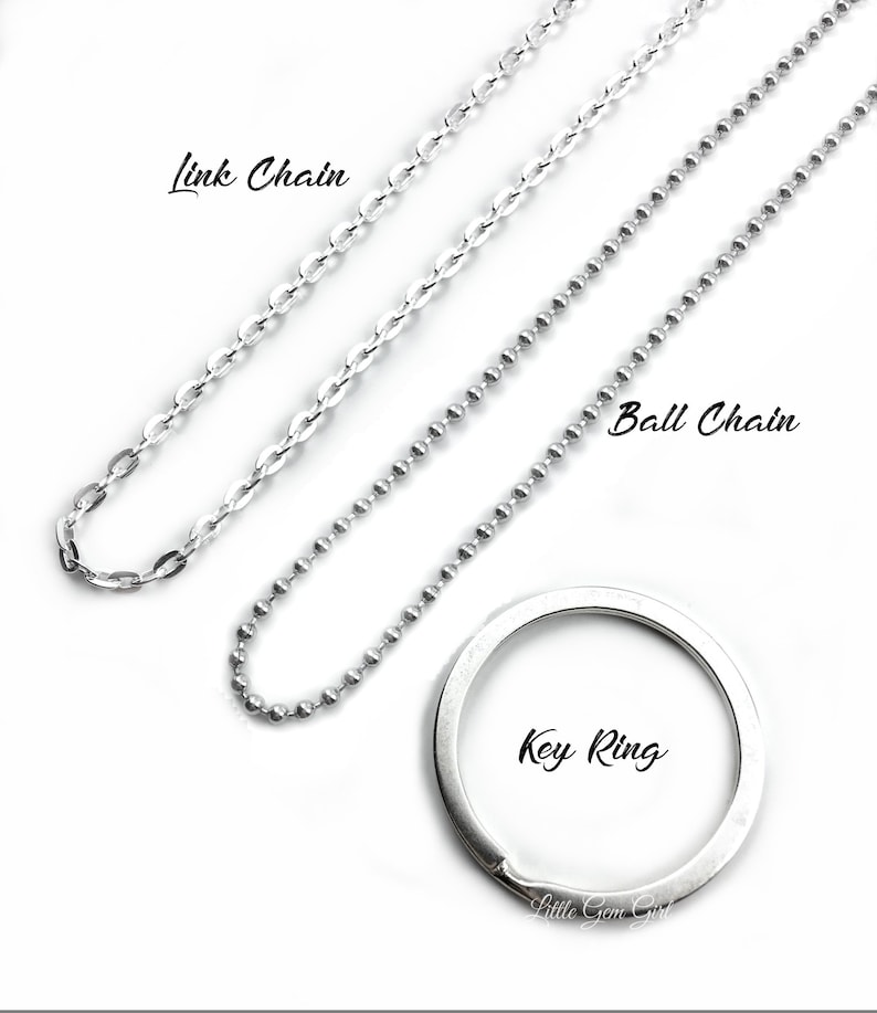 May include: Three silver chains, a link chain, a ball chain, and a key ring. The chains are laid out on a white surface.