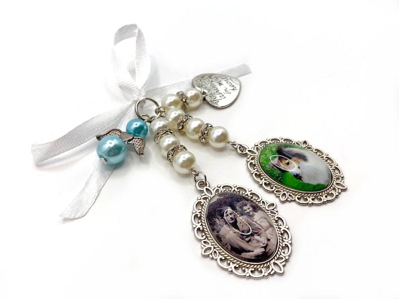 May include: A silver charm with a white ribbon, a heart charm with the text "Forever in my heart", a string of white pearls, a blue angel charm, and two oval photo charms. One photo charm features a dog, and the other features a family.