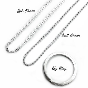 May include: Three silver chains, a link chain, a ball chain, and a key ring. The chains are laid out on a white surface.