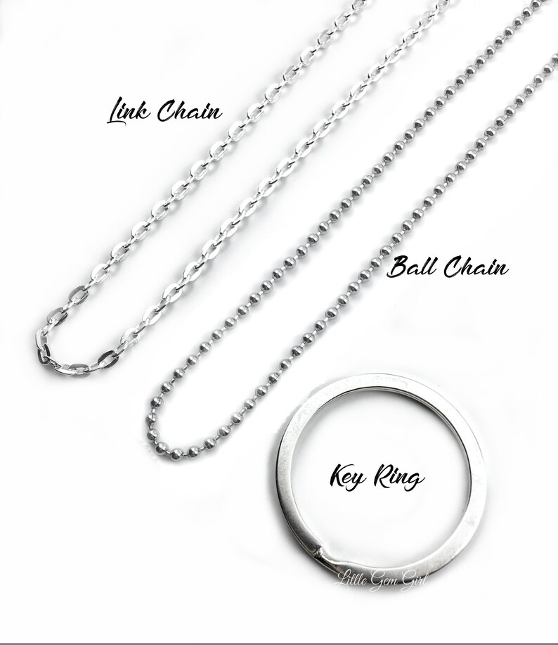 May include: Three silver chains, a link chain, a ball chain, and a key ring. The chains are laid out on a white surface.