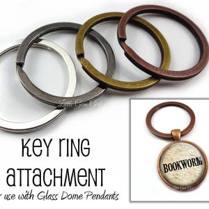 May include: Three silver, brass, and copper key rings for attaching glass dome pendants. The key rings are stacked on top of each other. The copper key ring has a glass dome pendant attached to it with the word "BOOKWORM" printed on the pendant.