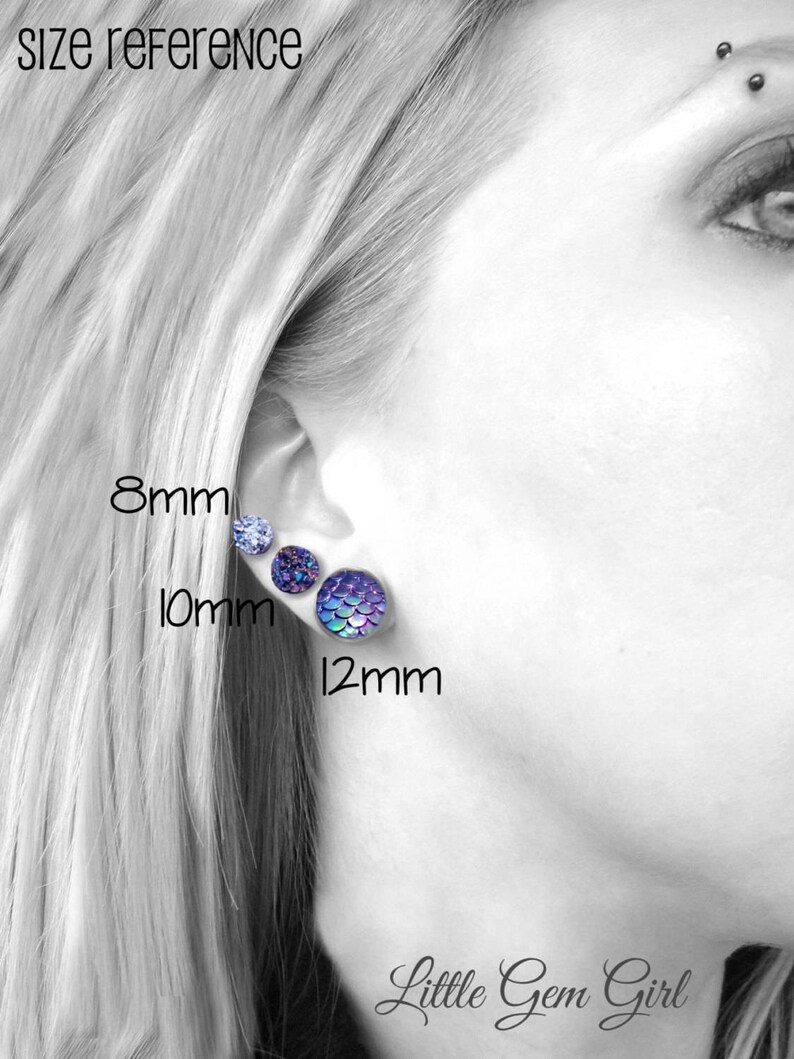 May include: Size reference for earrings showing three different sizes: 8mm, 10mm, and 12mm. The earrings are displayed on a person's earlobe. The earrings are iridescent and have a mermaid scale design.