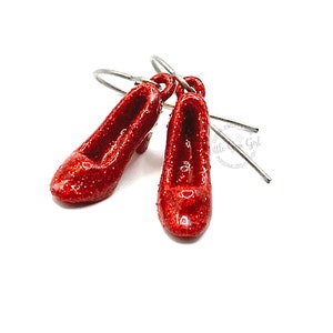 May include: A pair of red glitter ruby slipper earrings. The earrings are made of polymer clay and have a silver hook.