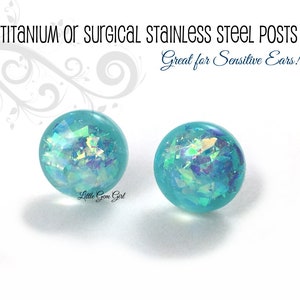 May include: A pair of turquoise blue stud earrings with iridescent glitter embedded in the resin. The earrings are made with titanium or surgical stainless steel posts. "Great for Sensitive Ears!" is written in the image.