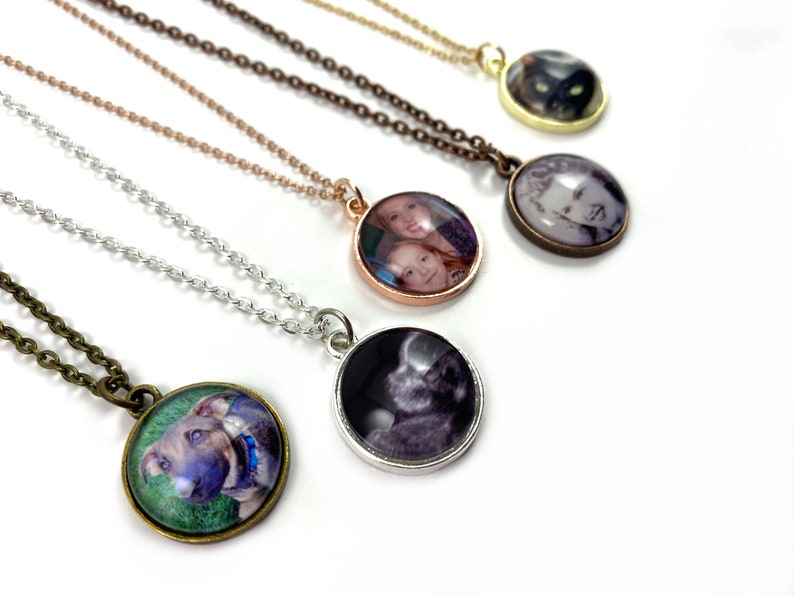 Puede incluir: Cinco collares con colgantes redondos de fotos. Los colgantes son de plata, oro, bronce, oro rosa y bronce antiguo. Cada colgante tiene una foto diferente en su interior. Los collares est&aacute;n sobre un fondo blanco.