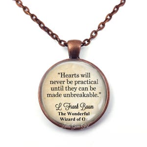 May include: A copper necklace with a glass pendant featuring a quote from L. Frank Baum's "The Wonderful Wizard of Oz": "Hearts will never be practical until they can be made unbreakable."