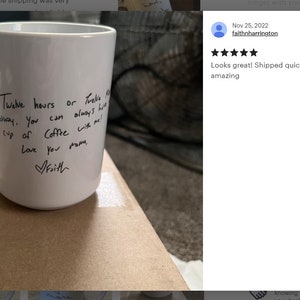 Może przedstawiać: Biały ceramiczny kubek do kawy z dużym uchwytem. Na kubku znajduje się odręczny tekst czarnym tuszem, kt&oacute;ry brzmi: "Twelve hours or twelve miles away. You can always have a cup of coffee with me! Love you mamo, Faith."