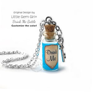 May include: A silver chain necklace with a small glass bottle pendant filled with blue liquid. The bottle has a cork stopper and a vintage-style label that reads "Drink Me". A silver key charm hangs from the bottle.