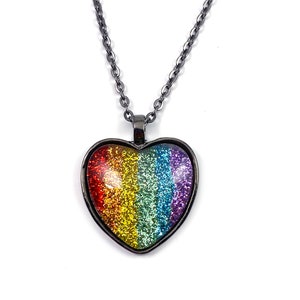 Peut inclure: Un collier en chaîne argentée avec un pendentif en forme de cœur. Le pendentif est rempli de paillettes arc-en-ciel.