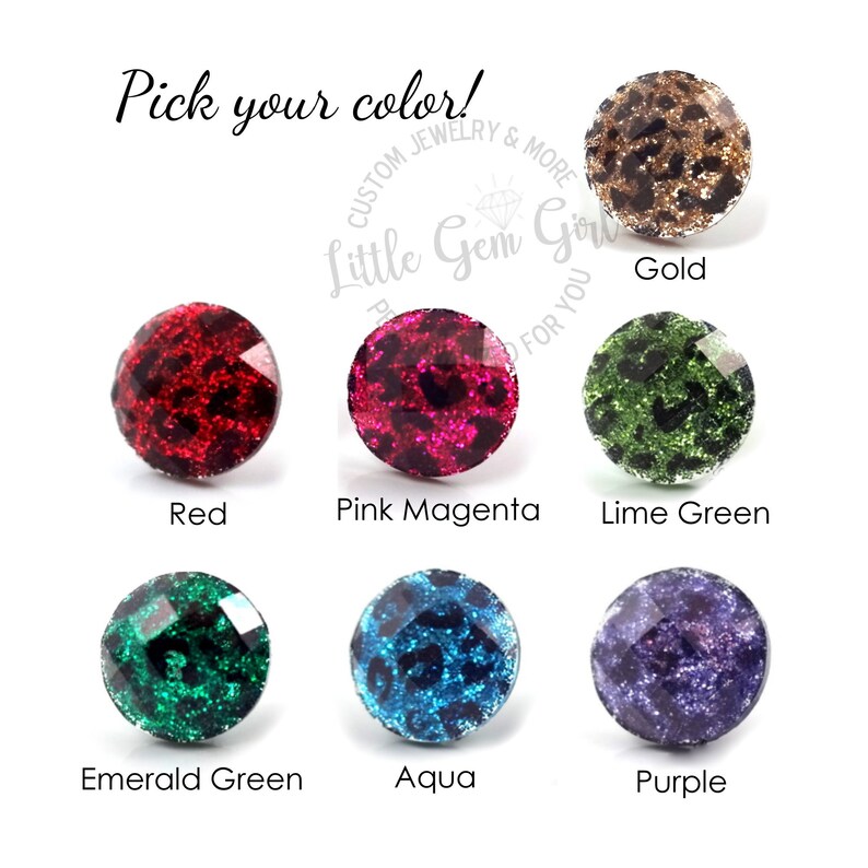 May include: A selection of round, glittery, decorative buttons in various colors, including red, pink, green, blue, and purple. The buttons feature a leopard print design. The text "Pick your color!" is at the top of the image. The text "Little Gem Girl" is in the center of the image. The text "Gold" is below the top button. The text "Red" is below the left button. The text "Pink Magenta" is below the center button. The text "Lime Green" is below the right button. The text "Emerald Green" is below the left button in the second row. The text "Aqua" is below the center button in the second row. The text "Purple" is below the right button in the second row.