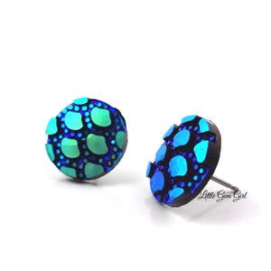 May include: A pair of blue and green iridescent stud earrings with a textured, scaly design. The earrings are made of polymer clay and have a silver post.