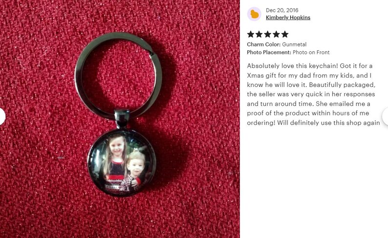 May include: A silver keychain with a round photo charm featuring a picture of two children. The charm is attached to a silver key ring.