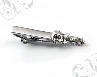 May include: Silver tie clip with a guitar design. The guitar is detailed with strings and a pickguard. The tie clip is a simple bar with a spring clip.