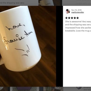 Może przedstawiać: Biały ceramiczny kubek z czarną, odręczną wiadomością, kt&oacute;ra brzmi "love, Louise Ann" i małym rysunkiem. Kubek ma uchwyt i jest trzymany przez osobę.