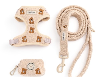 May include: A beige pet harness, leash, and pouch set. The harness and pouch feature a teddy bear pattern, and the leash is a matching fluffy material. The set includes a harness, a leash, and a small pouch with a zipper and a clip.