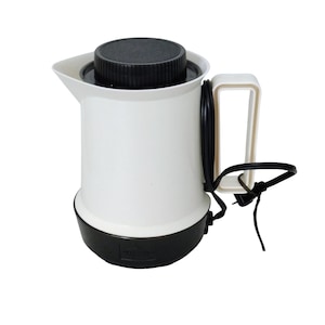 May include: A white electric kettle with a black base, lid, and power cord. The kettle has a handle and a spout for pouring. The power cord is black and attached to the side of the kettle.