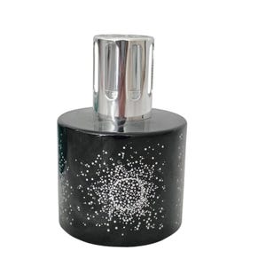 May include: A cylindrical black glass fragrance lamp featuring a white dotted starburst pattern around the body. The top of the vessel is fitted with a polished silver-colored metal crown cap with vertical cutouts for ventilation.
