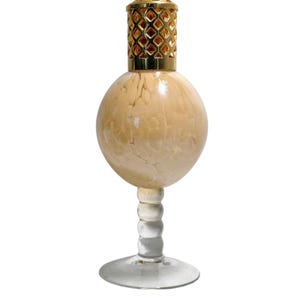 May include: An oil lamp with a cream-coloured, spherical body and a gold-coloured, diamond-patterned top. It stands on a clear glass stem and base, offering a vintage aesthetic. The lamp's height is approximately 18 cm.