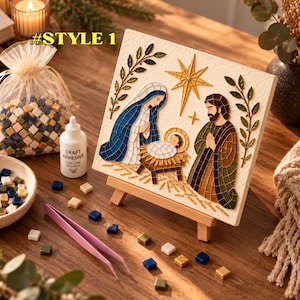 May include: A mosaic craft kit featuring a nativity scene on a square canvas displayed on a wooden easel. The kit includes a bag of small square tiles in blue, white, and gold, a bottle of craft adhesive, and pink tweezers for assembly.