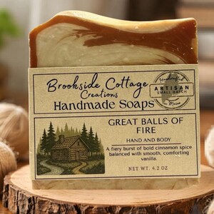 May include: A bar of handmade soap with a light brown and cream swirl design. The label reads "Brookside Cottage Creations Handmade Soaps" and "Great Balls of Fire". The net weight is 4.2 oz.