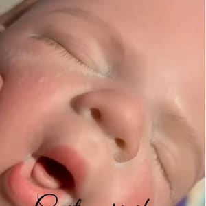 May include: A close-up of a baby doll's face, featuring closed eyes and a slightly open mouth. The doll has a realistic skin tone with details like eyelashes and a small nose. The text "Customers show" is written in cursive.