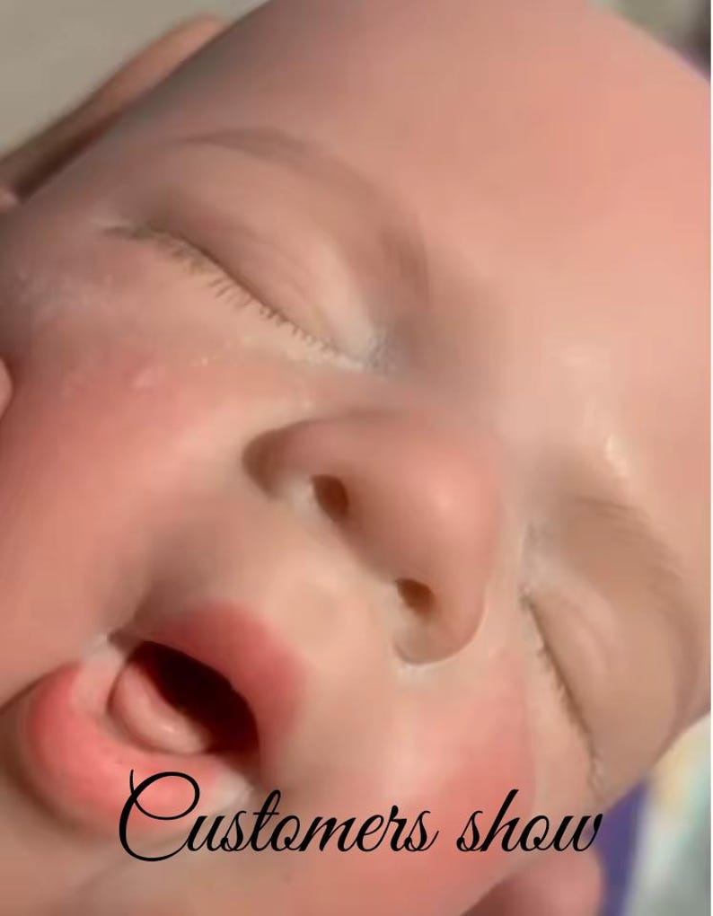 May include: A close-up of a baby doll's face, featuring closed eyes and a slightly open mouth. The doll has a realistic skin tone with details like eyelashes and a small nose. The text "Customers show" is written in cursive.