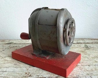 Vintage Bleistiftspitzer aus rotem Metall auf Holzsockel, manuelles Schreibtischaccessoire
