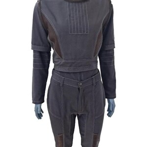 May include: A dark gray two-piece outfit with white stitching details. The top has a high collar and long sleeves, and the pants are fitted with pockets. The outfit is displayed on a mannequin.