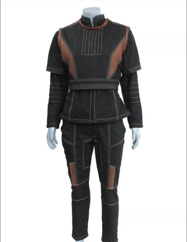 May include: A black two-piece outfit consisting of a short-sleeved top and matching pants. The top features a high collar, brown shoulder panels, and white topstitching. The pants have brown knee panels and white topstitching throughout the set.