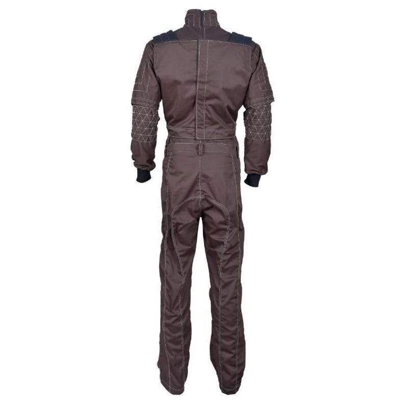 May include: A brown racing suit with white stitching and black accents. The suit has a high collar, long sleeves, and a fitted waist. The shoulders and sleeves feature geometric stitching patterns. The suit is designed for motorsports.