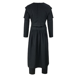 May include: A black two-piece outfit featuring a long-sleeved top with shoulder detailing and a long skirt. The skirt is paired with leggings. The outfit is made of a dark fabric and has a minimalist design.