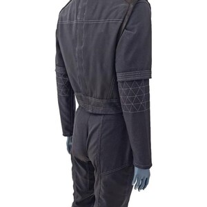 May include: Dark gray jumpsuit with white stitching details. Features include a stand-up collar, shoulder pads, and geometric patterns on the sleeves. The jumpsuit has a fitted waist and straight-leg pants.