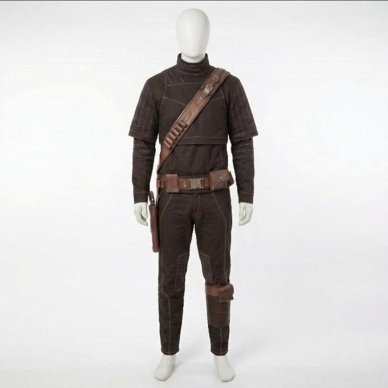 May include: A brown costume displayed on a mannequin. The outfit includes a high-collared top, trousers, and a belt with pouches. A leather shoulder strap and leg holster are also visible. The costume has a tactical design.