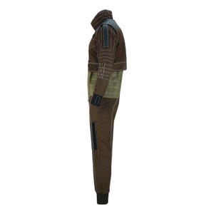 May include: Brown jumpsuit with a high collar, featuring geometric stitching and a contrasting olive green midsection. The outfit includes a jacket and matching pants, with black accents on the sleeves and legs. The jumpsuit is designed for a close fit.