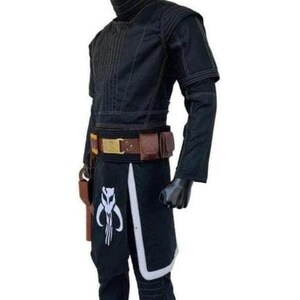 Op de afbeelding: Zwart kostuum met een hoge kraag, bruine riem met zakjes en een holster. De broek heeft een wit en zwart ontwerp met een symbool. Het kostuum wordt op een mannequin gepresenteerd.
