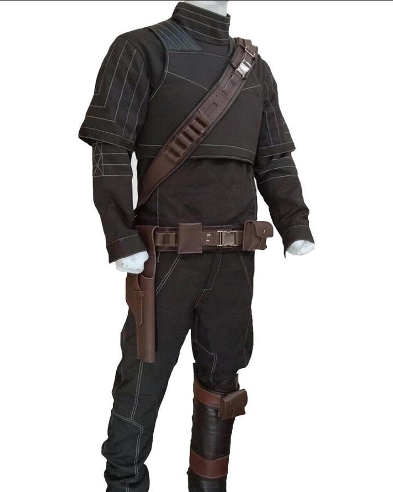 May include: A black costume with brown accents, featuring a high collar, shoulder straps, and a utility belt. The outfit includes a holster, knee pads, and stitching details. The costume is designed for cosplay or themed events.