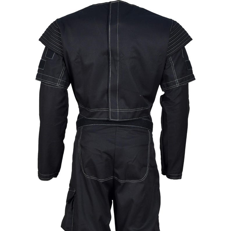 Puede incluir: Mono negro con costuras blancas. La prenda presenta mangas largas, un dise&ntilde;o de hombros estructurado y bolsillos cargo en los pantalones cortos. La vista trasera muestra el ajuste entallado y las costuras blancas contrastantes.