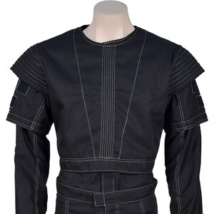 Puede incluir: Mono negro con costuras blancas. La prenda presenta un cuello redondo, mangas largas y cintura con cintur&oacute;n. Los hombros tienen detalles estructurados y superpuestos con costuras blancas. Dise&ntilde;o elegante y moderno, adecuado para diversas ocasiones.