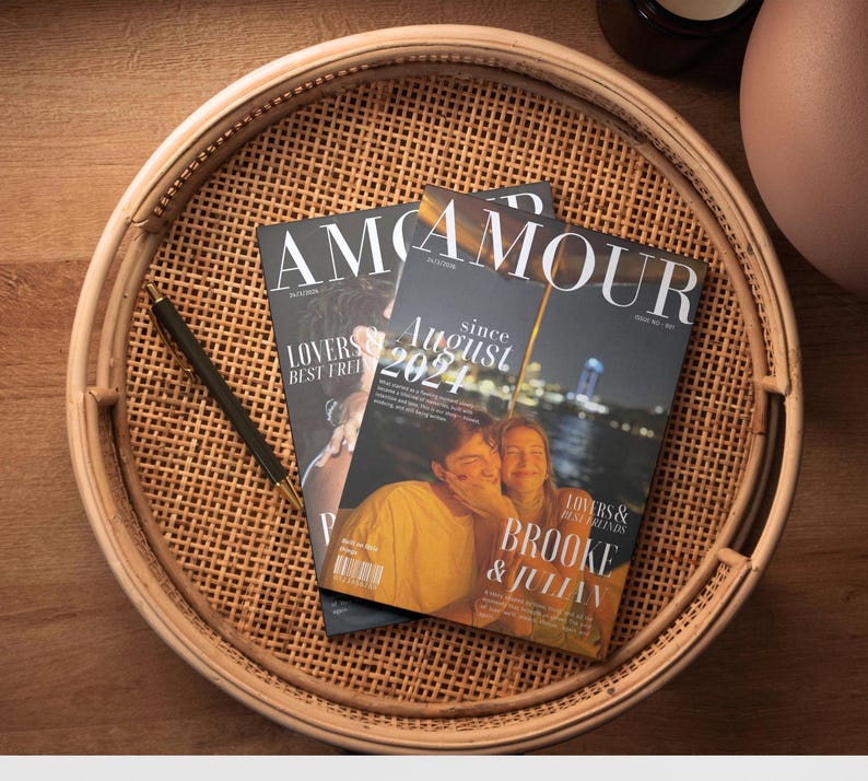 May include: Two magazines with the word "AMOUR" on the cover are on a woven tray. One magazine has the text "LOVERS & BEST FRIENDS" and the other says "since August 2021". A black pen rests on the tray.