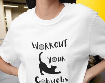 May include: A white short-sleeved t-shirt featuring a black graphic of a stretching cat and the text "WORKOUT your Cobwebs" with small spiderweb icons replacing the letter "O" in the words, printed in a simple black sans-serif font.