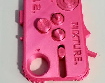 May include: A bright pink, 3D-printed device with the word "MIXTURE" and the number "12." visible. The device has several buttons, a dial, and a lever. It appears to be a control panel or a component of a larger system.