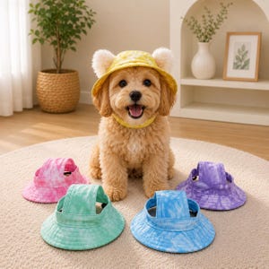 May include: A light-colored, fluffy dog wearing a yellow tie-dye bucket hat with ear holes. Four additional tie-dye bucket hats in pink, green, blue, and purple are arranged in front of the dog on a circular rug, each featuring a wide brim and strap.