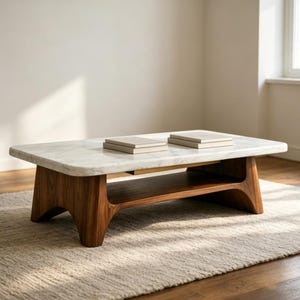 Może przedstawiać: Prostokątny stolik kawowy z białym marmurowym blatem i podstawą z ciemnego drewna. Podstawa ma dolną półkę i mosiężny akcent. Dwie prostokątne książki znajdują się na powierzchni stołu. Stół stoi na dywanie w neutralnym kolorze.