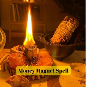 May include: A lit candle with a tall flame, surrounded by orange crystals and a small bowl with a bundle of sage. The text "Money Magnet Spell" is displayed in a yellow box.
