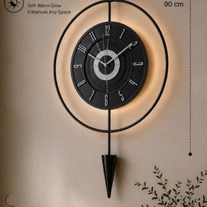 Puede incluir: Un reloj de pared negro moderno con un diseño circular y retroiluminación LED. La esfera del reloj tiene números y manecillas blancas. El reloj mide 90 cm de alto y 50 cm de ancho, con el texto "LED BACKLIGHT" y "Soft Warm Glow Enhances Any Space".