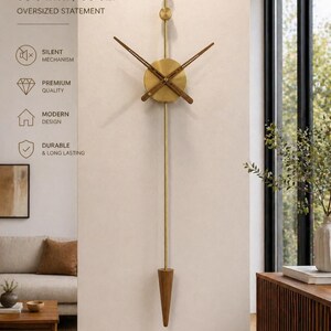 May include: A long, brass-colored wall clock with a wooden pendulum and clock hands. The clock face is circular with a wooden center. The text "33.5 inch / 85 cm" and "OVERSIZED STATEMENT" are visible. The clock is labeled as having a silent mechanism, premium quality, modern design, and being durable.