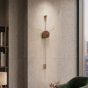 May include: A modern wall clock with a minimalist design. The clock features a round, dark wood face with gold-colored hands and a long, gold pendulum. The clock is mounted on a textured, light gray wall.
