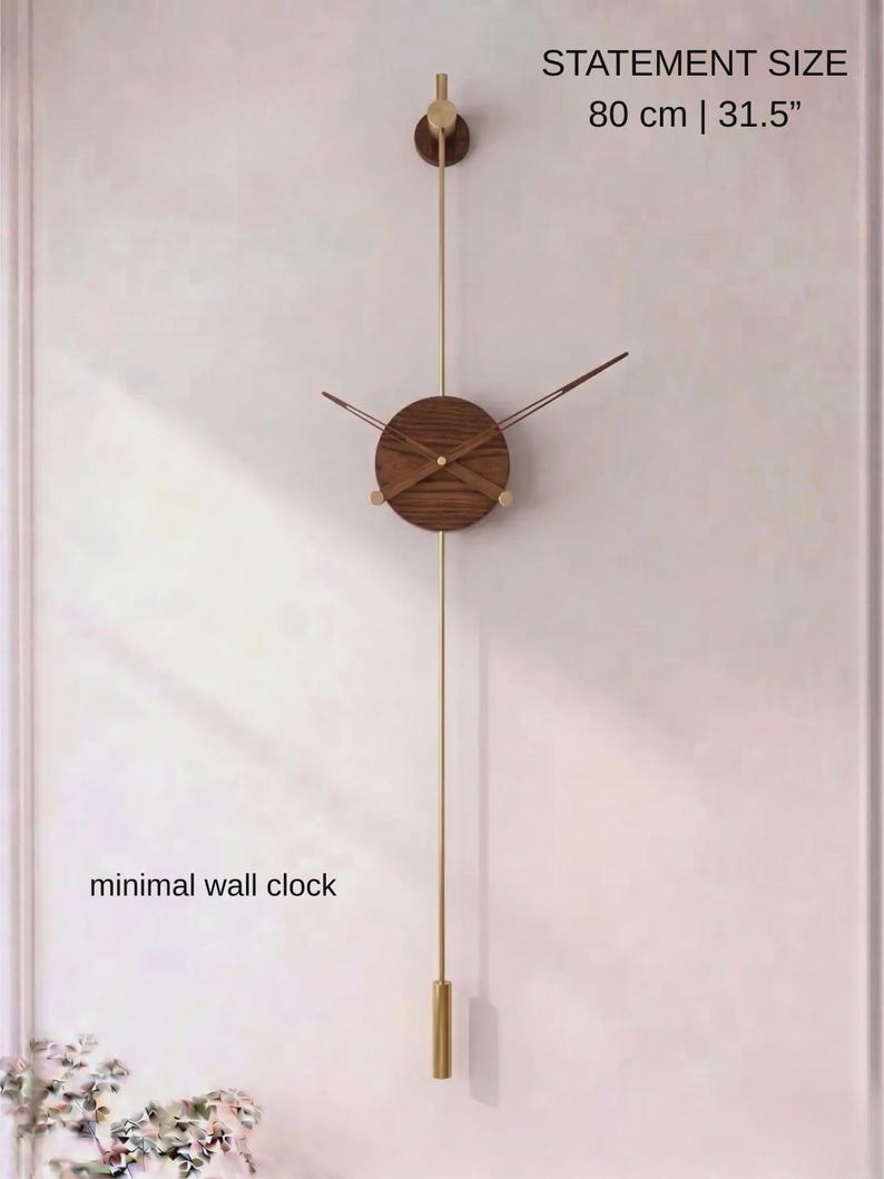 May include: A minimalist wall clock with a wooden face and brass accents. The clock is 31.5 inches in length and features a long pendulum. The text "STATEMENT SIZE 80 cm | 31.5" is visible. The words "minimal wall clock" are also visible.