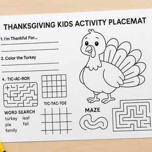 Op de afbeelding: Thanksgiving placemat voor kinderen met een kalkoenillustratie, doolhoven en een woordzoeker. Bevat prompts om op te schrijven waar je dankbaar voor bent en de kalkoen te kleuren. Kleurpotloden in blauw, oranje, geel en groen liggen verspreid.